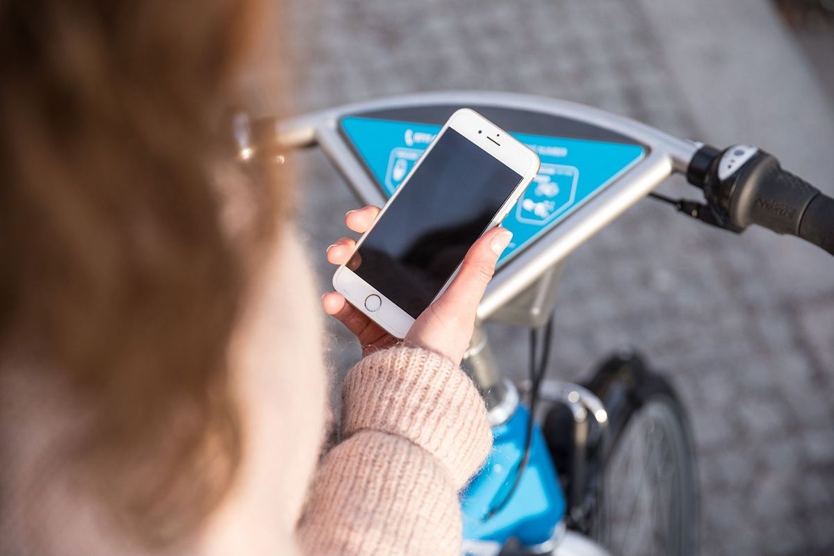 Frau lädt & registriert die RegioRadStuttgart App vor Fahrrad
