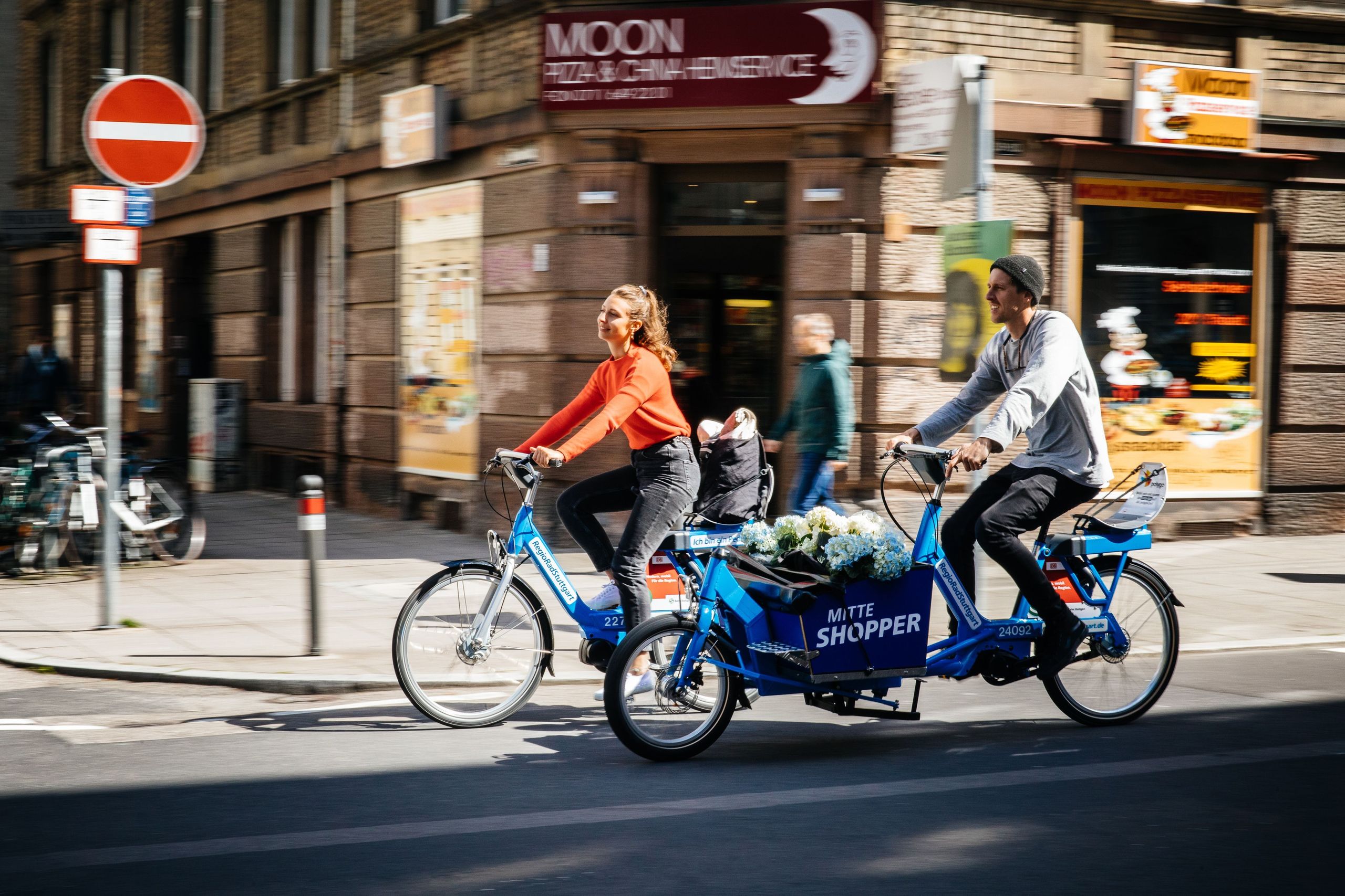 Man and woman ride through the city with RegioRadStuttgart pedelec and cargo pedelec
